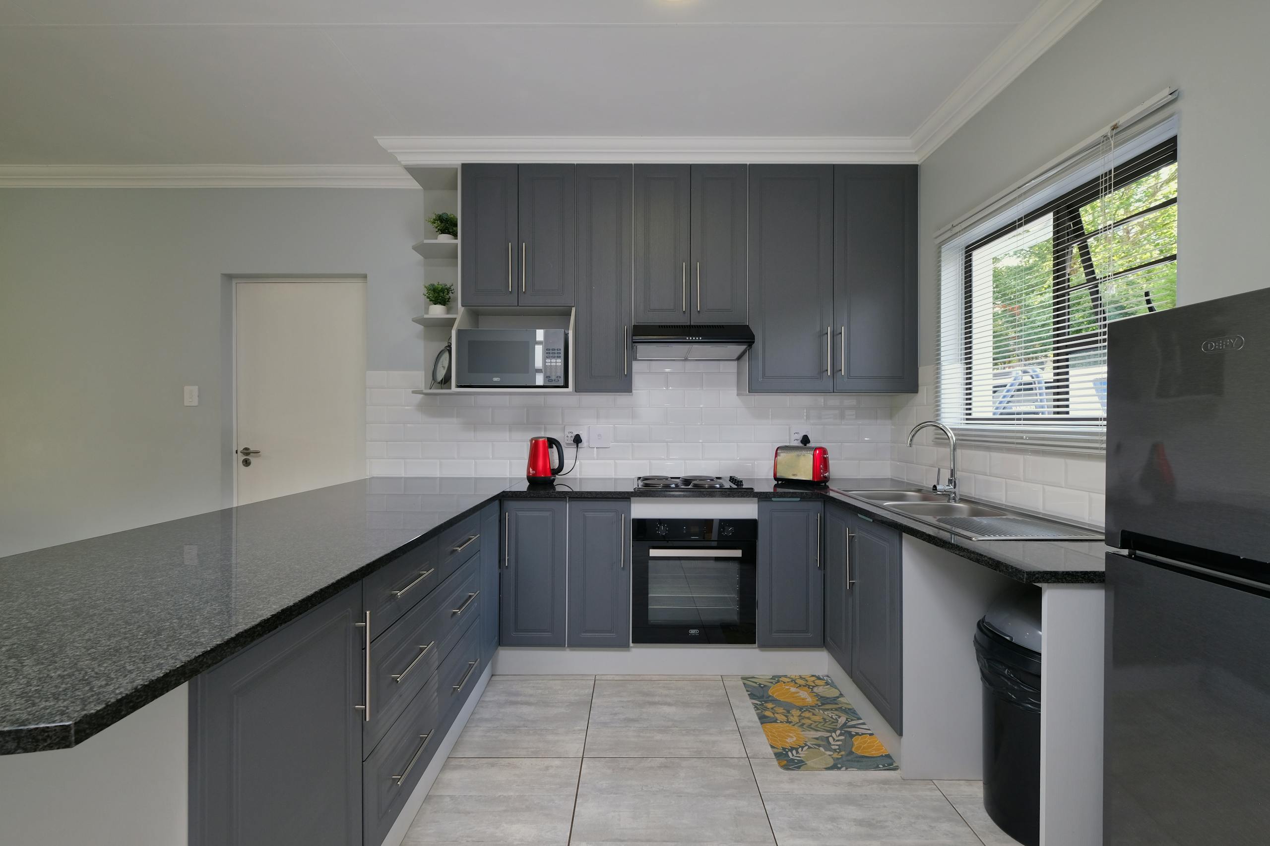 Sleek modern kitchen featuring grey cabinets and stainless steel appliances.